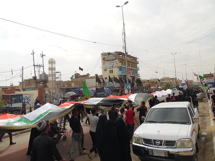 بالصور: شباب يتكفلون بخياطة علم العراق بطول (135) متر وعرض (4.5)متر، ويسيرون تحته الى كربلاء باسم شهداء العراق